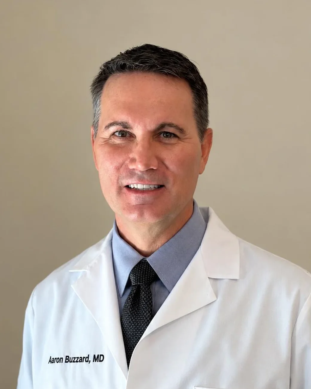 Dr. Aaron Buzzard, MD, smiling, in a white coat at Precision Medical Aesthetics.